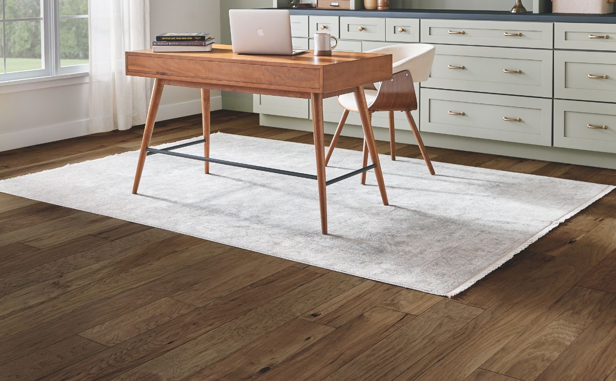 area rugs in a home office with wood look floors and sage green cabinetry